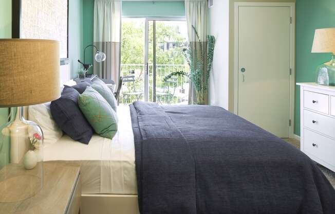 a bedroom with green walls and a bed with a gray blanket