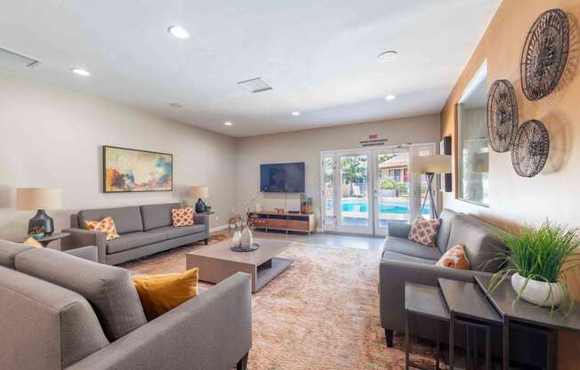 A living room with grey couches and a painting on the wall.