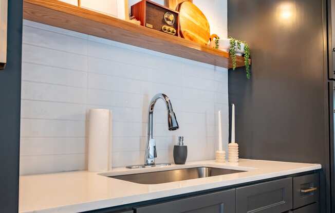 a kitchen with black cabinets and white counter top and a sink