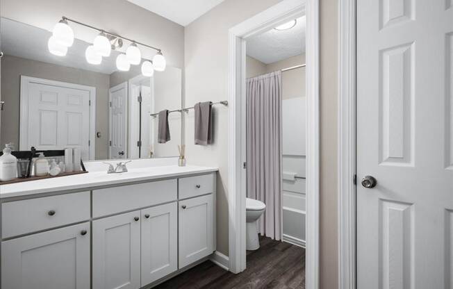 a bathroom with white cabinets and a white toilet next to a white sink