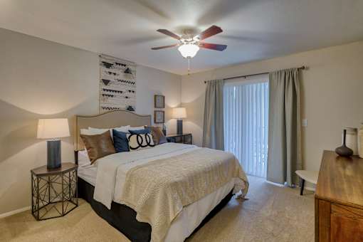 A bedroom with a large bed and a ceiling fan.