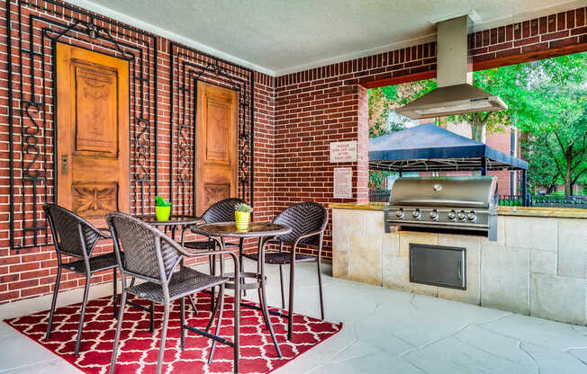 A patio with a table and chairs and a grill.