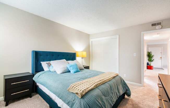 A bedroom with a blue headboard and a bed with a green comforter.
