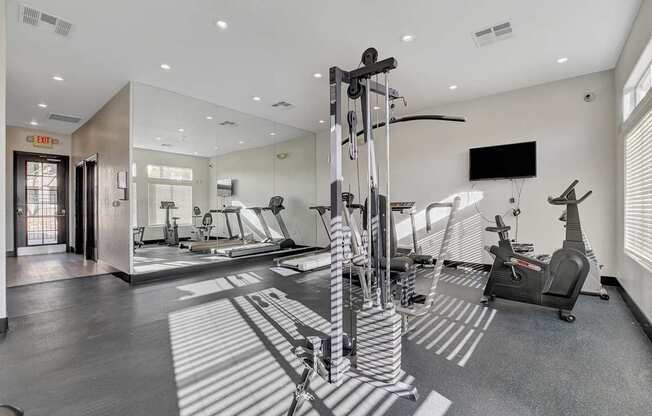A gym with a variety of equipment including a treadmill, a stationary bike, and a weight machine.