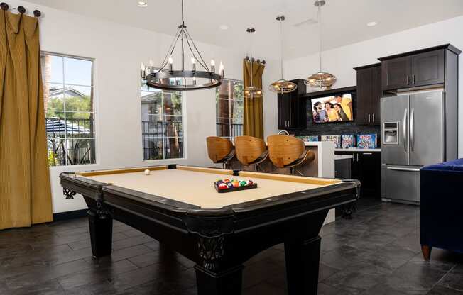a billiards table in a living room with a kitchen and television