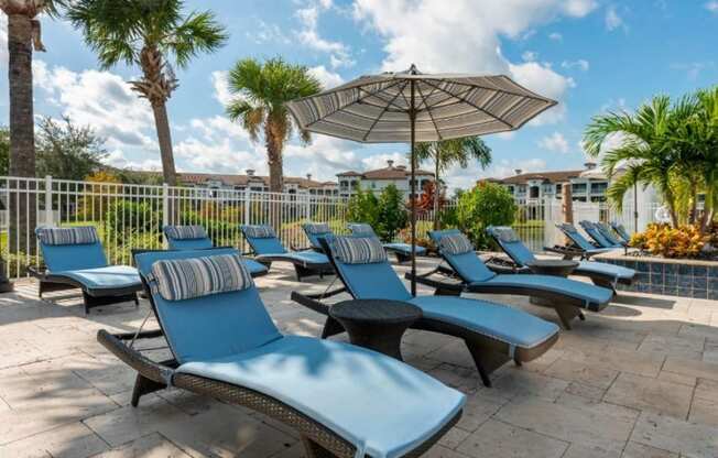 a pool with lounge chairs and an umbrella at the preserve at great pond apartments in windsor