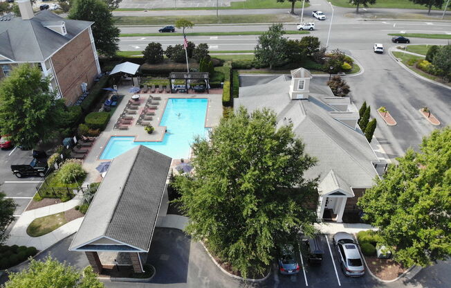 a large swimming pool surrounded by a parking lot and a brick building