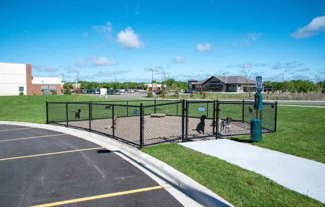 A parking lot with a black fence and a green trash can.