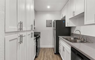 A kitchen with white cabinets and a black refrigerator.
