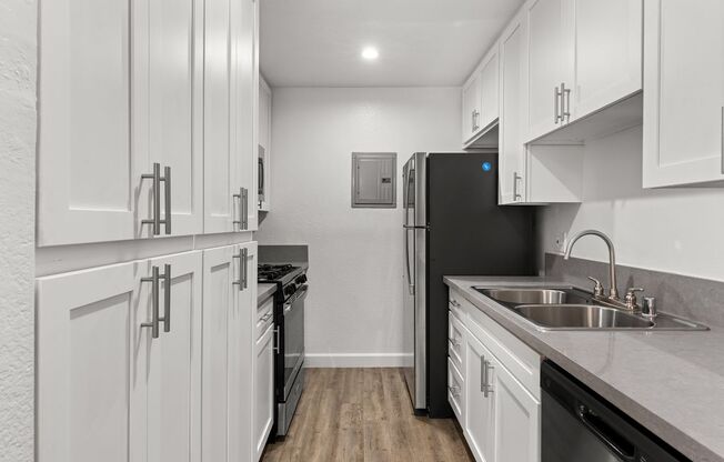 A kitchen with white cabinets and a black refrigerator.