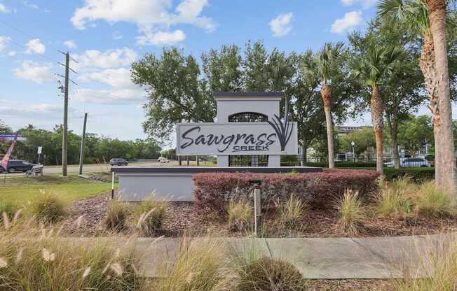 A sign that says Sawgrass in front of some trees.