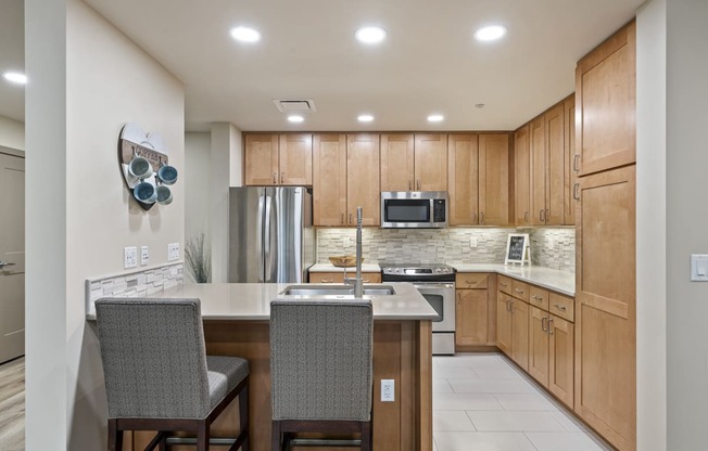 a kitchen with wooden cabinets and an island with two chairs