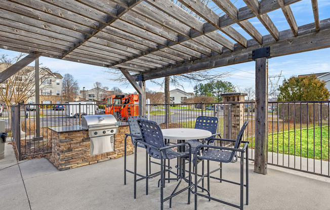A patio with a table and chairs under a wooden pergola.