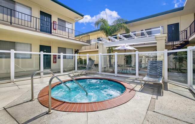 a jacuzzi in the middle of a pool in front of a building at Olive Tree Apartments, Torrance, CA 