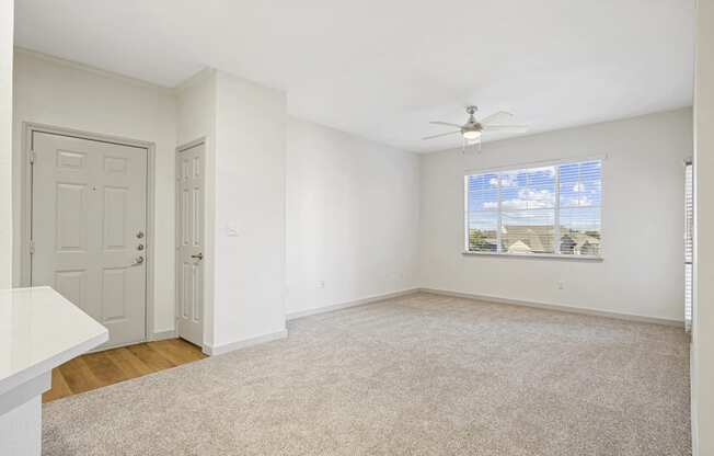 an empty living room with white walls and a ceiling fan