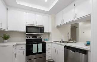 a kitchen with white cabinets and black and white counter tops at Huntington Terrace North Senior, Huntington Beach California