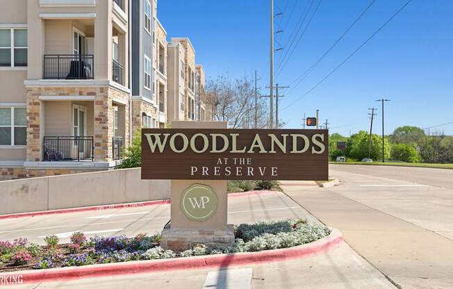 A sign that says Woodlands at the Preserve in front of some buildings.