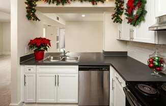 A kitchen with a black countertop and a stove with a wreath above it.