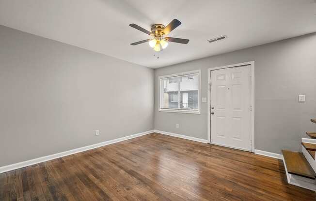 an empty living room with wood floors and a ceiling fan