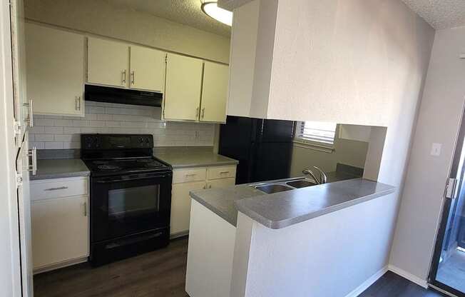 an empty kitchen with white cabinets and black appliances