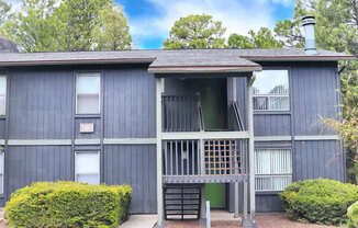 A two-story building with a balcony and a green door.