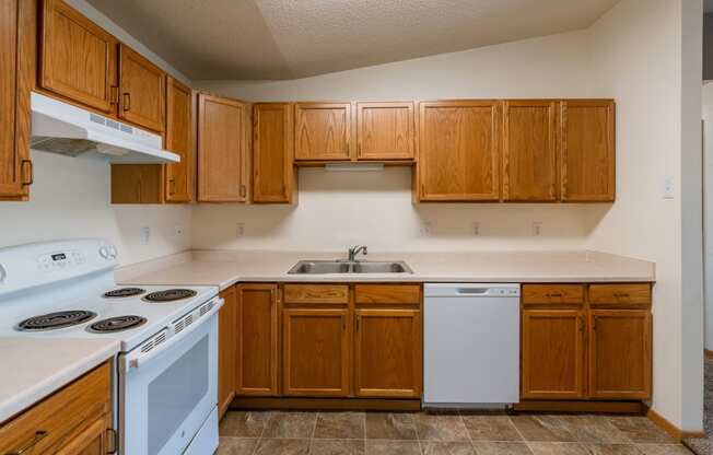 a kitchen with white appliances and wooden cabinets.  Fargo, ND Sunwood Apartments  | Living and kitchen Fargo, ND Sunwood Apartments