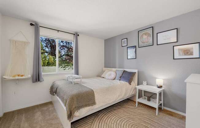 A bedroom with a bed, nightstand, and pictures on the wall at Clackamas Trails Apartments, Oregon, 97222