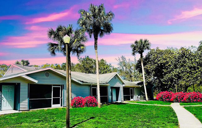 A blue house with palm trees in front of it at Aqua Bay Apartments in Naples, FL 34116