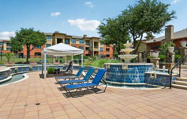 A pool area with a white canopy and blue lounge chairs.