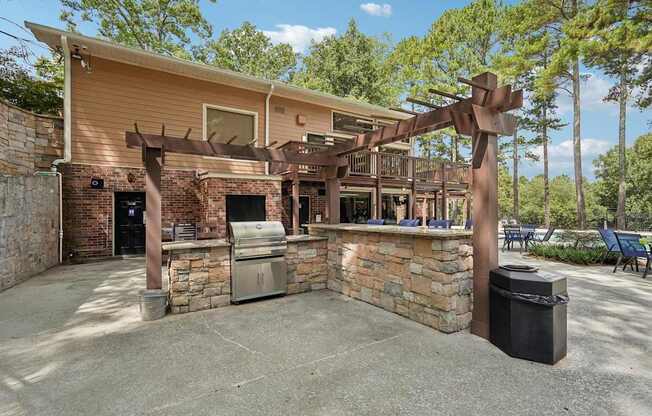 A patio area with a stone wall and a wooden pergola.