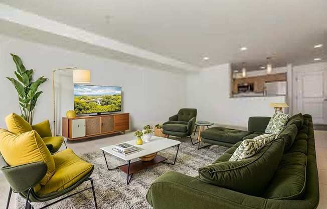 A living room with a green couch, yellow chair, and a television.