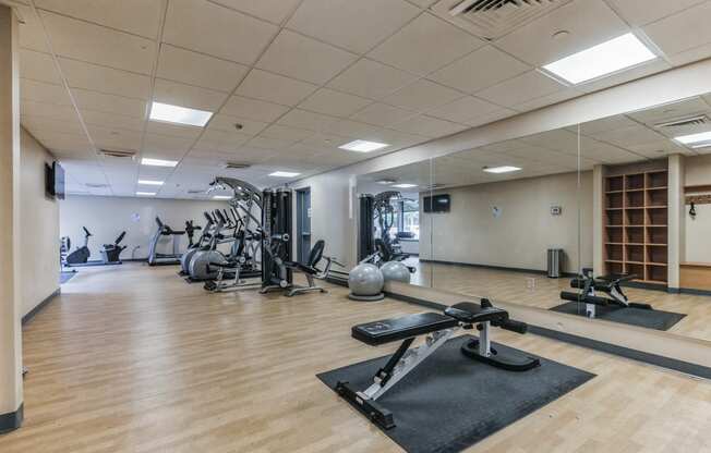 a gym with weights and other exercise equipment in a room with wooden floors