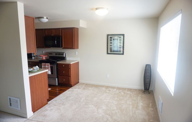 a kitchen and dining area with a carpeted floor and large window at Heritage Grove Apartments in Renton, WA