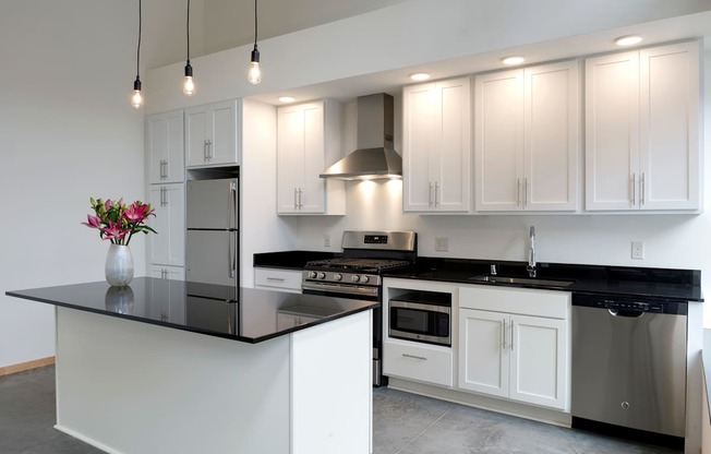 A modern kitchen with white cabinets and black countertops.