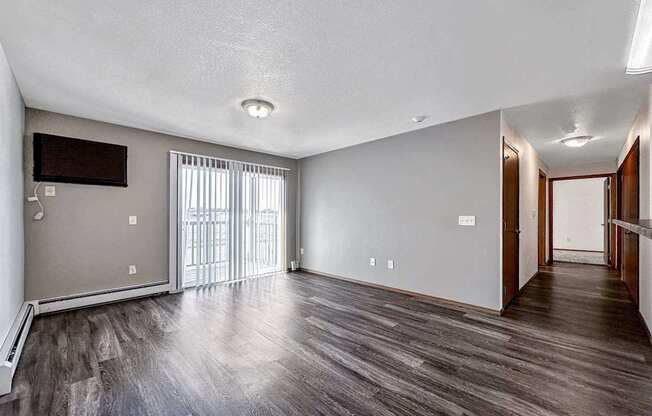 an empty living room with wood flooring and a sliding glass door