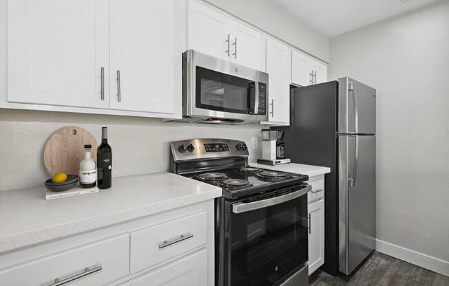Model Kitchen with White Cabinets and Wood-Style Flooring at Crystal Creek Apartments in Phoenix, AZ.