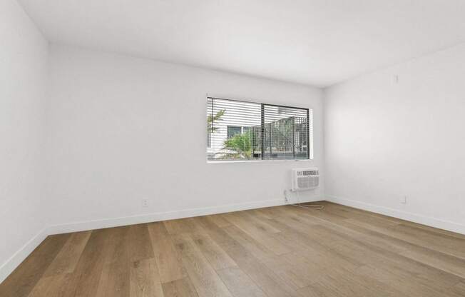 an empty living room with white walls and a window