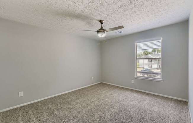 A room with a ceiling fan and a window with blinds.