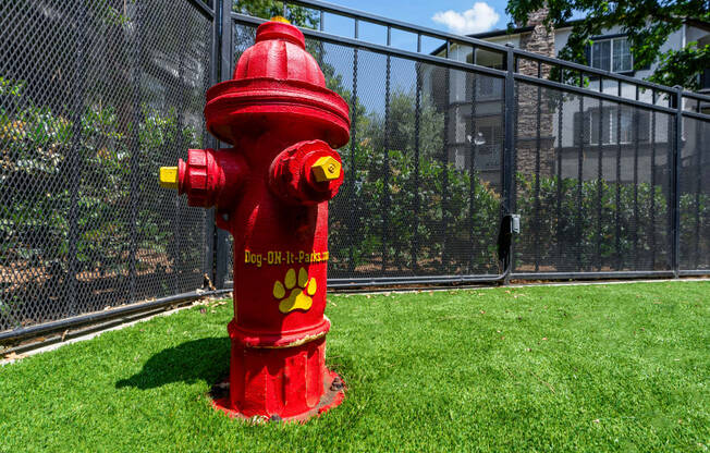 a red fire hydrant in the grass next to a fence