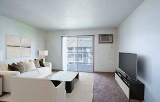 A living room with a white couch and a flat screen TV. Fargo, ND Stonebridge Apartments