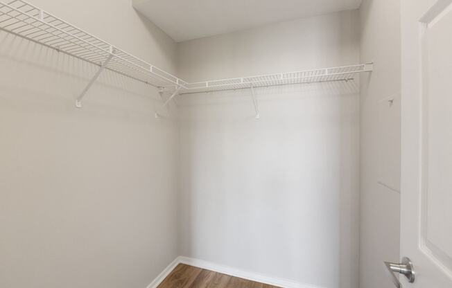 an empty room with a white wall and a wire rack on the wall