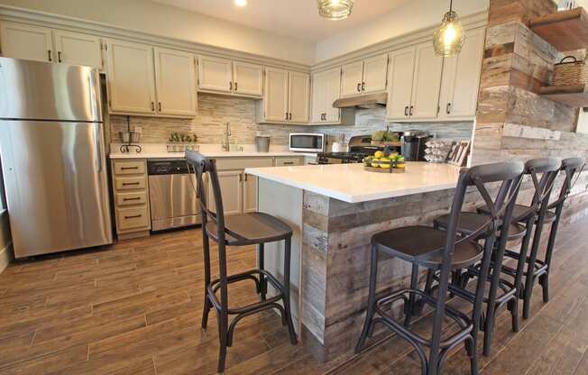 A kitchen with a large island and chairs.