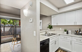 a kitchen with white cabinets and a black dishwasher