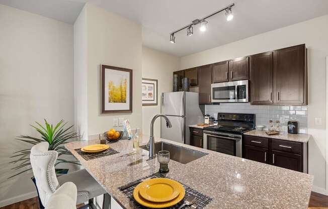 A kitchen with a granite countertop and stainless steel appliances. at Bridge at Southpark Meadows, Austin, TX