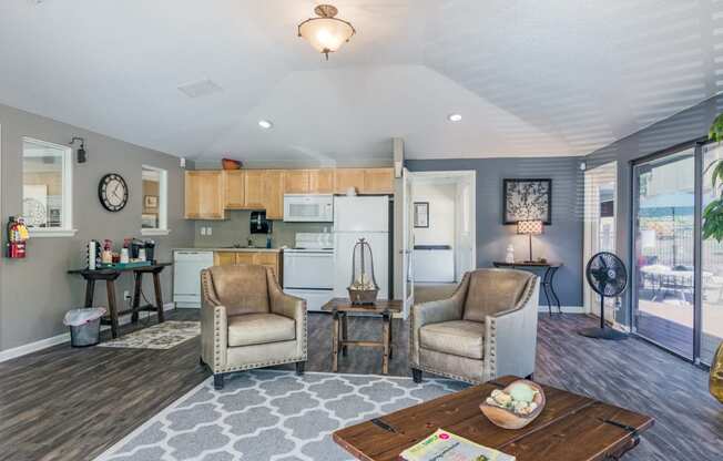 a living room with two chairs and a table and a kitchen