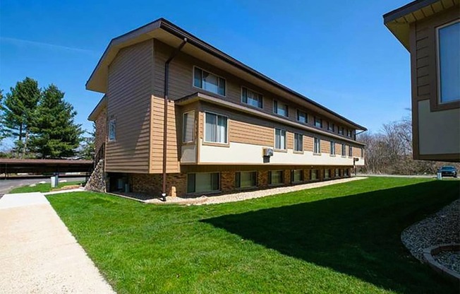 a large building with a green lawn and a sidewalk