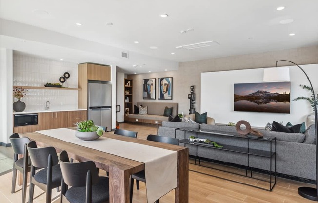 A modern living room with a wooden dining table and grey sofa.