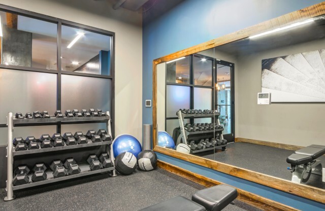 The fitness center at our Washington DC apartments, featuring a mirrored wall, exercise balls, and free weights.