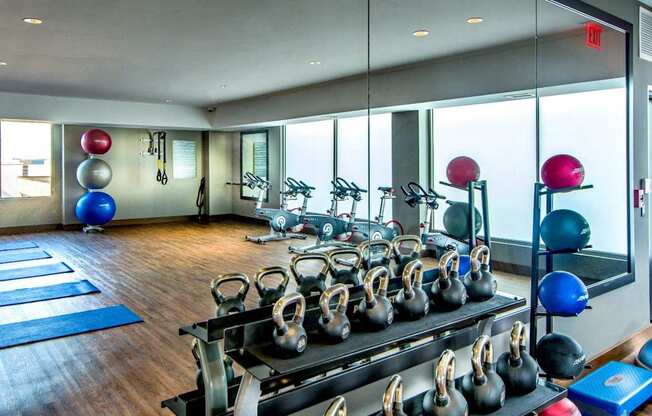 A gym with a row of kettlebells on a rack.