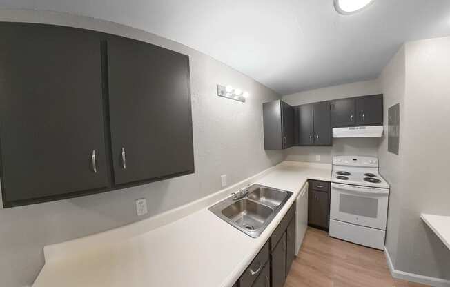 an empty kitchen with black cabinets and white appliances